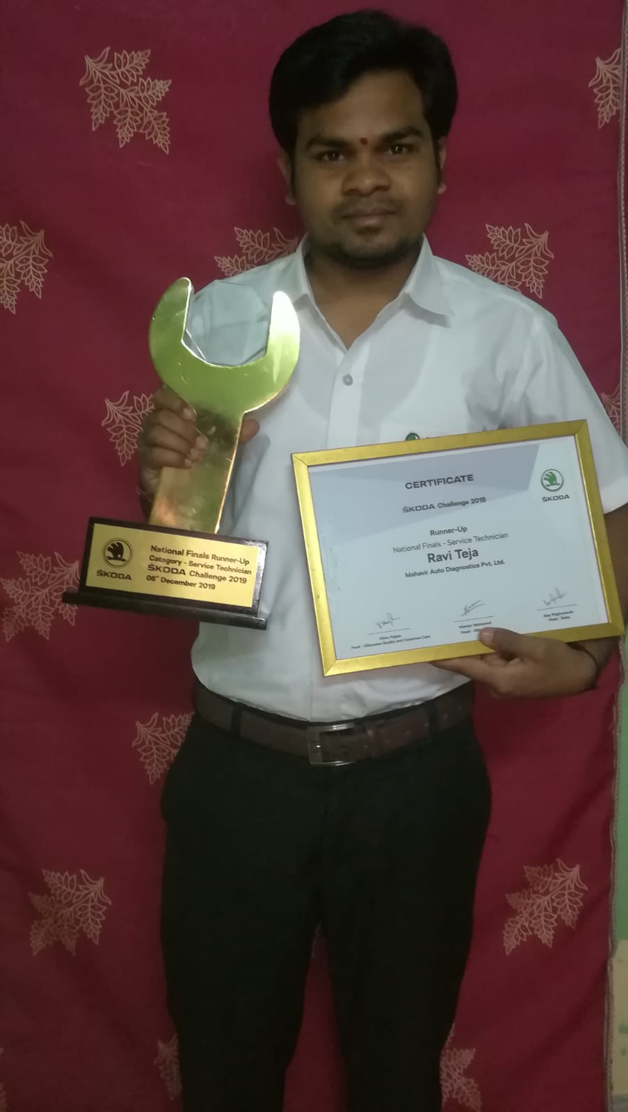 Technician holding Škoda Challenge 2019 trophy and certificate